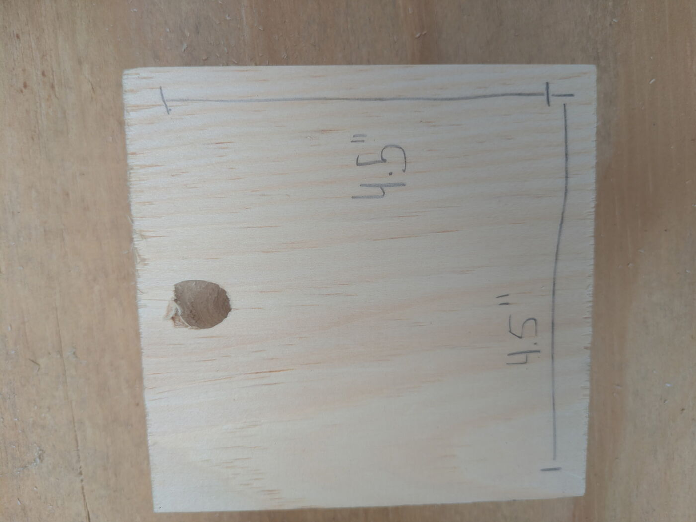The top of a pine lid with an eye hook and chain screwed into the center.