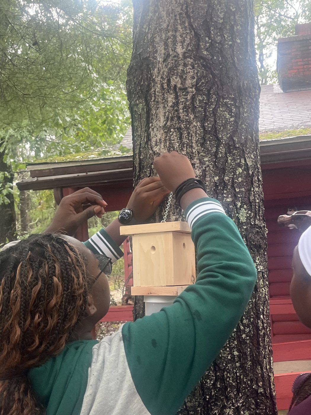 Close-up of a Girl Scout attaching a finished bee trap to a tree trunk.